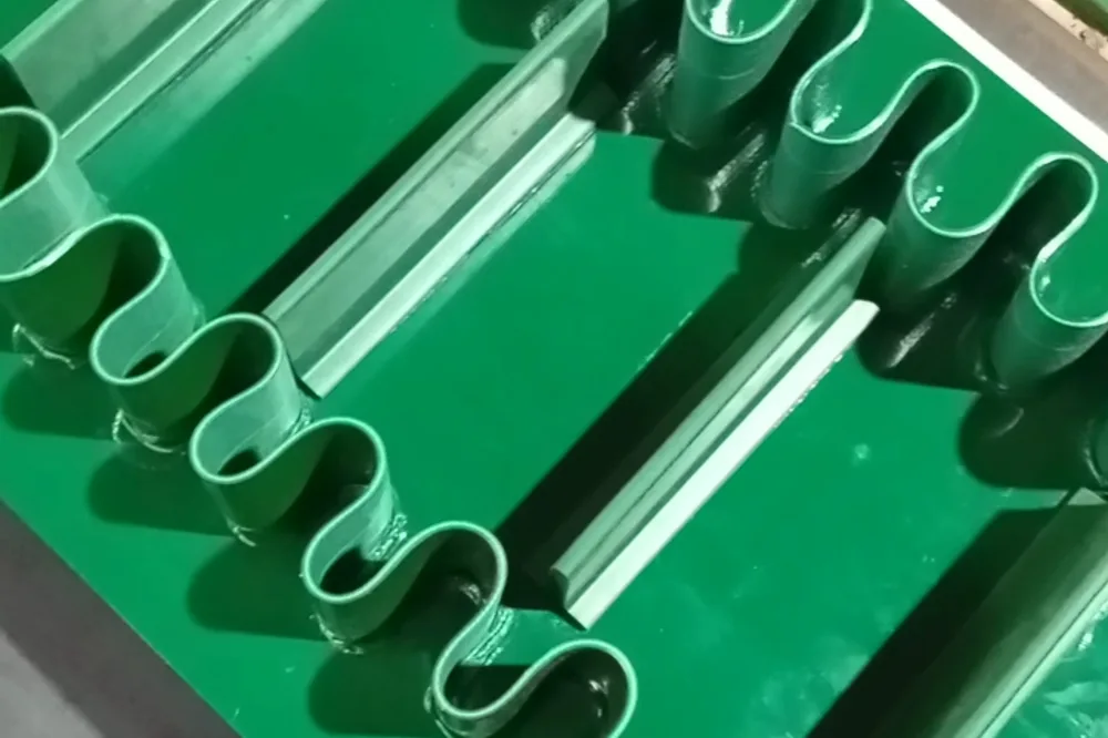 Deretan cleat bergelombang hijau terpasang di punggung belt PVC, dilihat dari dekat di bidang kerja