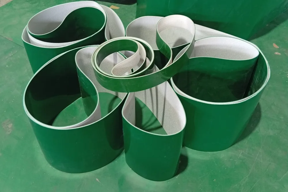 Beberapa belt PVC hijau yang telah disambung endless tergeletak melingkar di lantai workshop