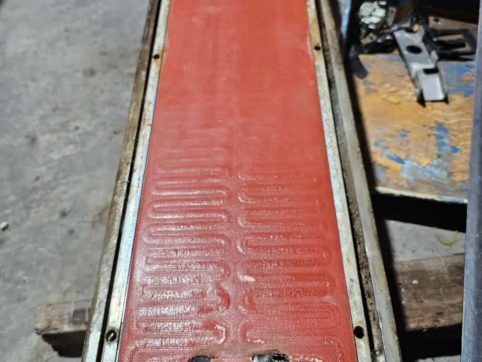 Plat pemanas merah pada mesin press vulkanisasi, dilihat memanjang di sepanjang bed press